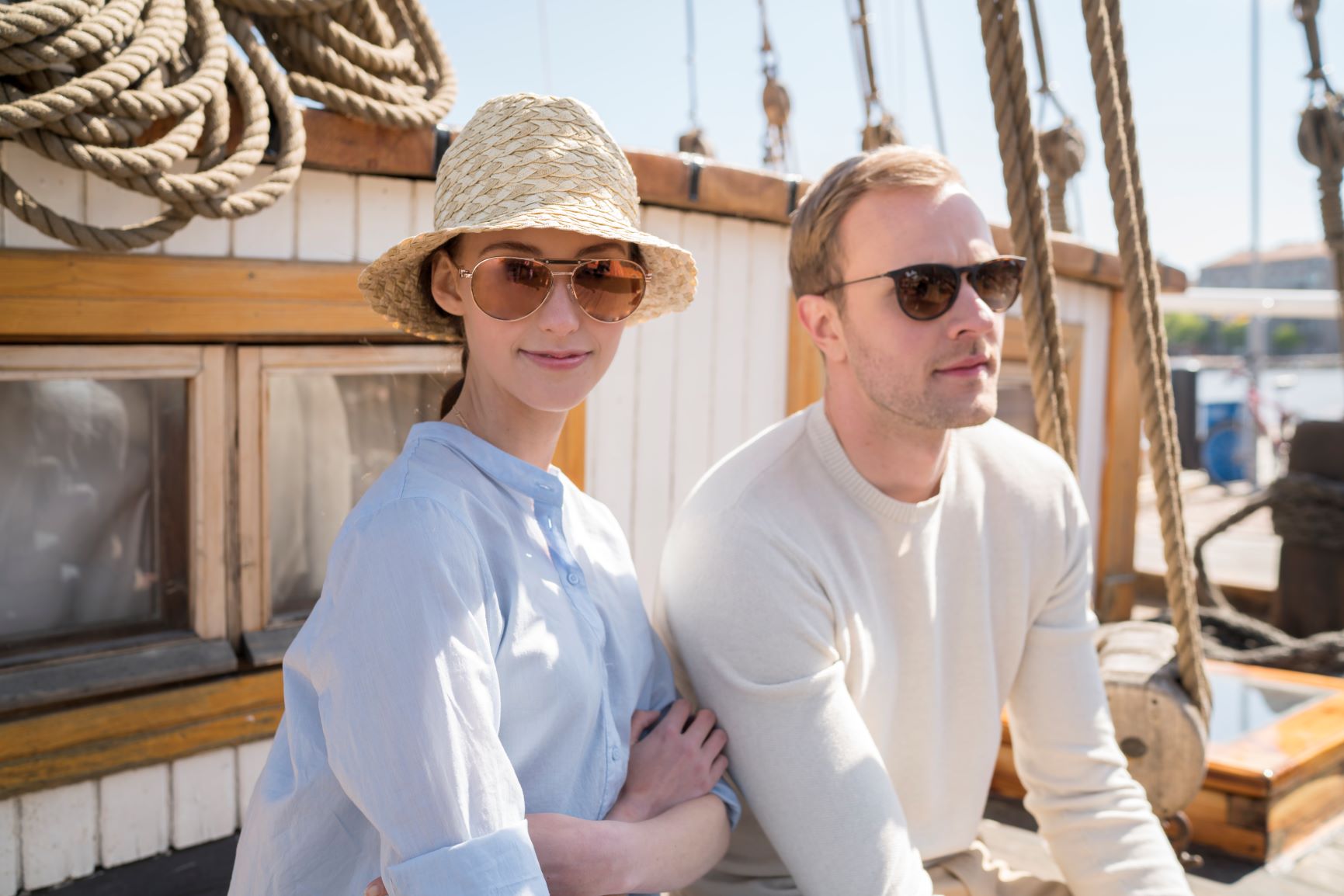 Mies ja nainen aurinkolasit päässä veneen kannella